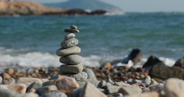 Pirámide de guijarros equilibrada en la playa al atardecer - Foto, imagen