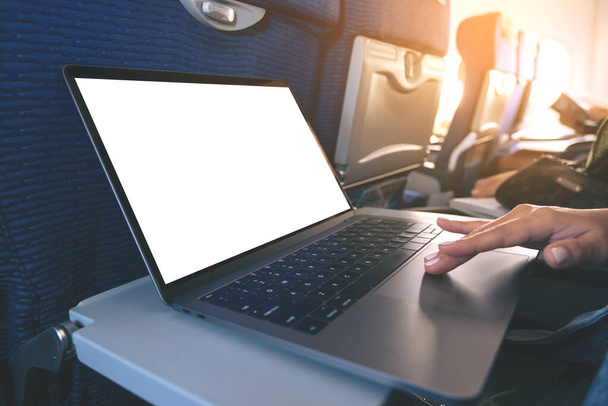 Mockup image of a woman using and touching on laptop computer touchpad with blank white desktop screen while sitting in the cabin - 写真・画像