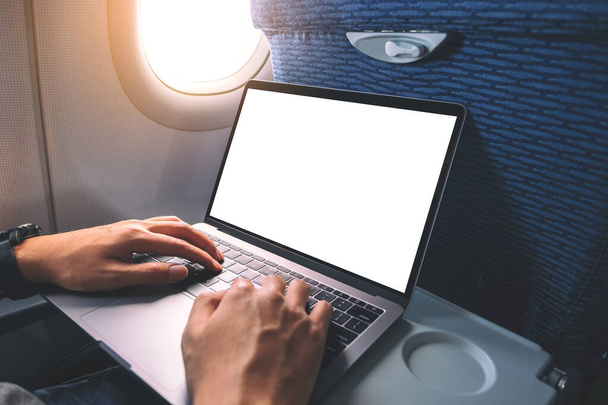Mockup image of a man using and typing at laptop computer with blank white desktop screen while sitting in the cabin - Фото, зображення