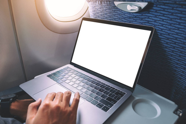Mockup image of a man using and touching on laptop computer touchpad with blank white desktop screen while sitting in the cabin - Valokuva, kuva