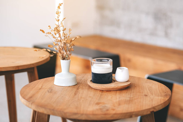 Крупним планом зображення келиха лате на дерев'яному столі в мінімальному кафе
 - Фото, зображення