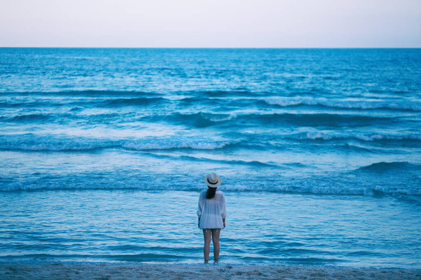 A woman standing on the beach, looking at a beautiful sea and blue sky alone - Foto, afbeelding