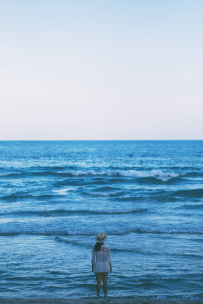 Una mujer de pie en la playa, mirando un hermoso mar y el cielo azul solo - Foto, imagen