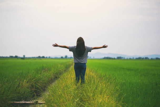 Жінка стоїть і розтягує руки в красивому рисовому полі з відчуттям розслабленості і свіжості
 - Фото, зображення