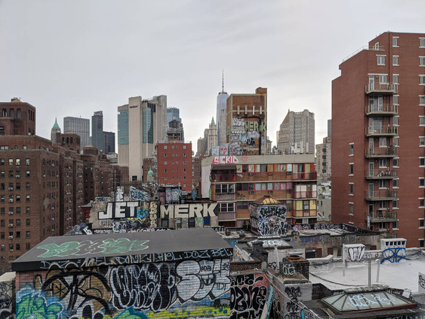 New York City, USA - December 27 2020: Cityscape of lower Manhattan with buildings covered in graffiti and modern skyscrapers in the background - Photo, image