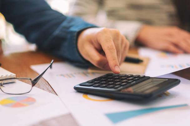 Крупный план бизнесмена с помощью калькулятора на деловой встрече - Фото, изображение
