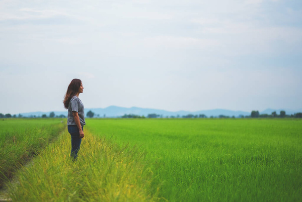 Kobieta stojąca i patrząca na piękne pole ryżowe z poczuciem relaksu i spokoju - Zdjęcie, obraz