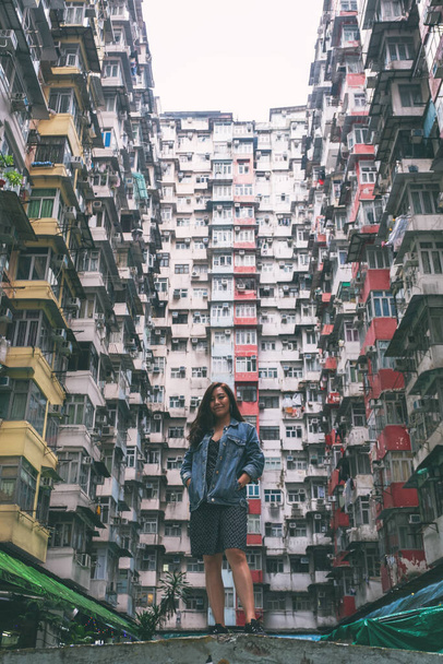 Piękna azjatycka kobieta stojąca pośród zatłoczonego budynku mieszkalnego społeczności w Quarry Bay w Hongkongu - Zdjęcie, obraz