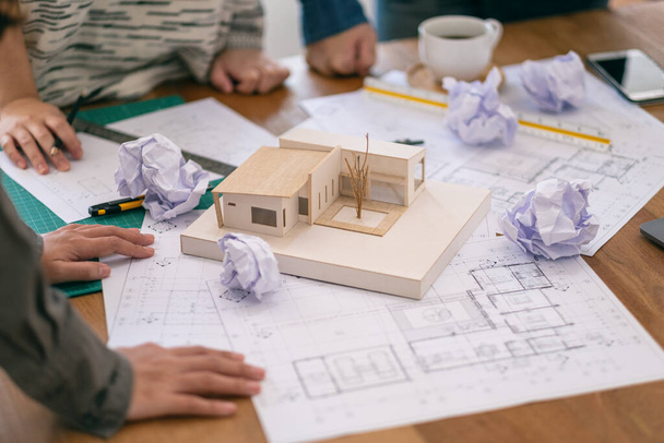 Group of an architect feel stressed after working on architecture model together with shop drawing paper on table in office - Photo, Image