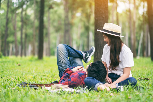 Ένα νεαρό ζευγάρι Ασιατών ερωτευμένων κάθεται και ξαπλώνει μαζί στο πάρκο. - Φωτογραφία, εικόνα