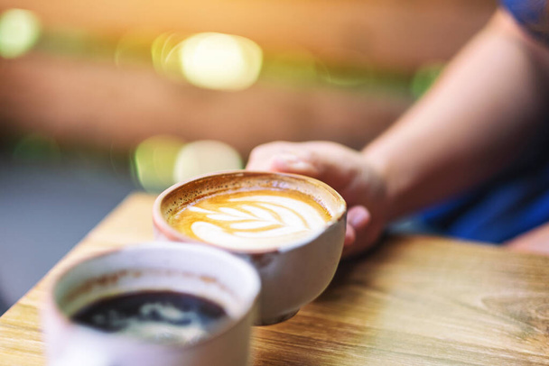 Immagine ravvicinata di due persone che afferrano tazze da caffè su un tavolo di legno  - Foto, immagini