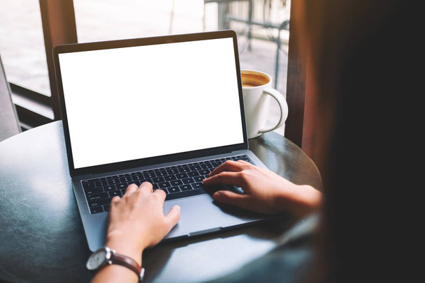 Imagem Mockup de uma woamn usando e digitando no laptop com tela de desktop branca em branco com xícara de café na mesa  - Foto, Imagem