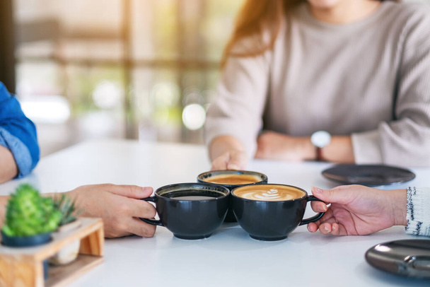 Immagine primo piano di persone goduto di bere e clinking tazze di caffè sul tavolo in caffè - Foto, immagini