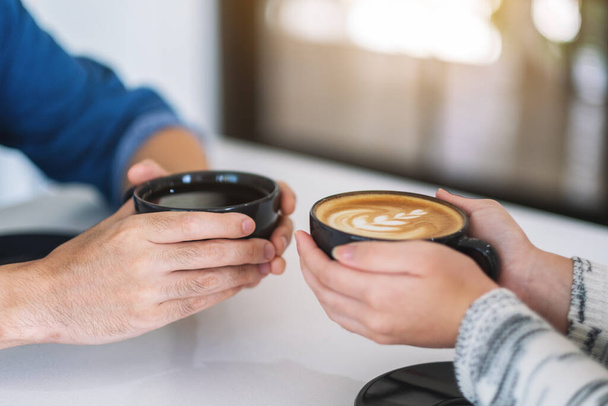 Κοντινή εικόνα ενός άνδρα και μιας γυναίκας που κρατούν δύο φλιτζάνια καφέ ενωμένα - Φωτογραφία, εικόνα