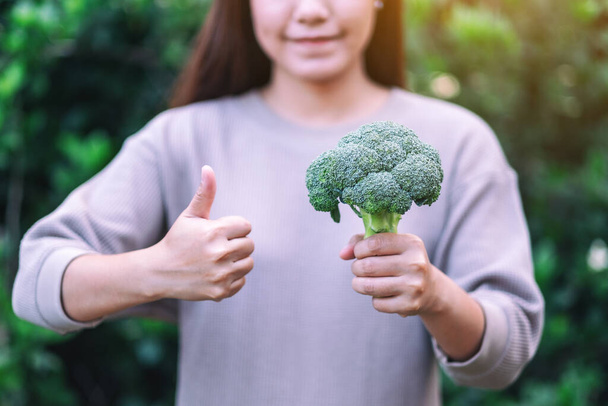 žena drží palec nahoru, aby ukázala dobré znamení zelené brokolici  - Fotografie, Obrázek