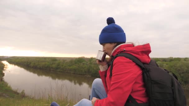 Dziewczyna pije herbatę z kubka siedzącego na wysokiej górze i cieszącego się przyrodą w parku. Podróżująca kobieta szuka przygody. Odpręż się na wycieczce. Wędrówki długodystansowe. Ludzki odkrywca - Materiał filmowy, wideo