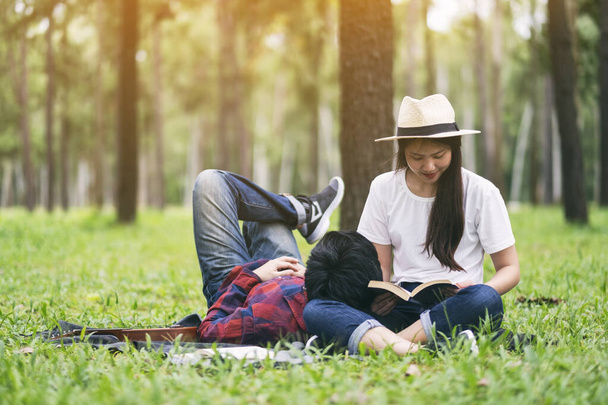 A young asian lover couple reading book and lying down together in the park - Photo, Image