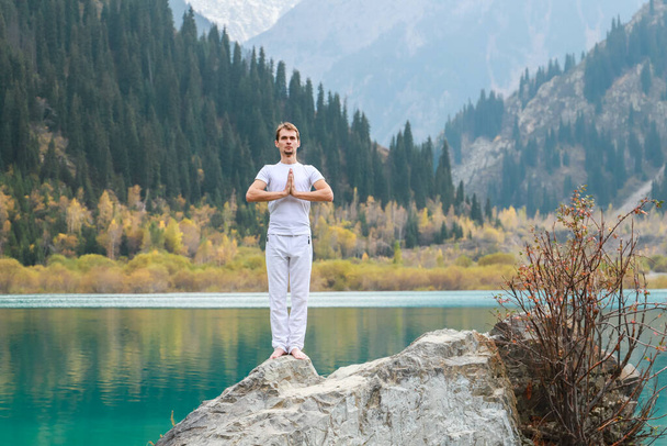 Un joven zen meditando. Yoga al aire libre en lago de montaña. - Foto, imagen