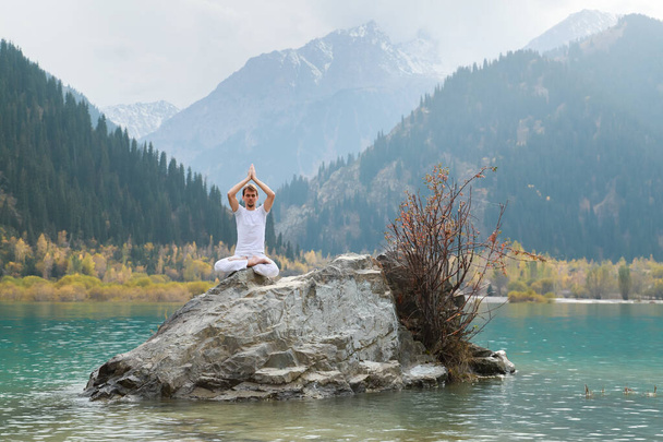 Junger Zen-Mann in Meditation. Outdoor-Yoga im Bergsee. Übung Agni Stambhasana. - Foto, Bild