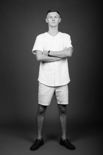 Giovane uomo che indossa camicia bianca contro sfondo grigio - Foto, immagini
