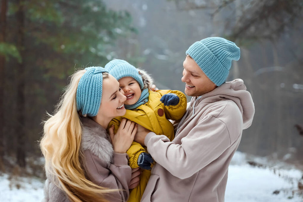 Happy family Dad, mom and baby sy on a winter walk in the forest. Concept for christmas, family, relatives, vacations, fresh air - Photo, Image