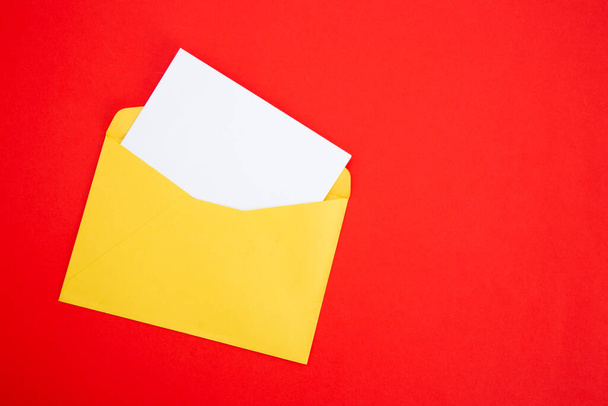 Kleurrijke papieren enveloppen op rode achtergrond - bovenaanzicht - Foto, afbeelding