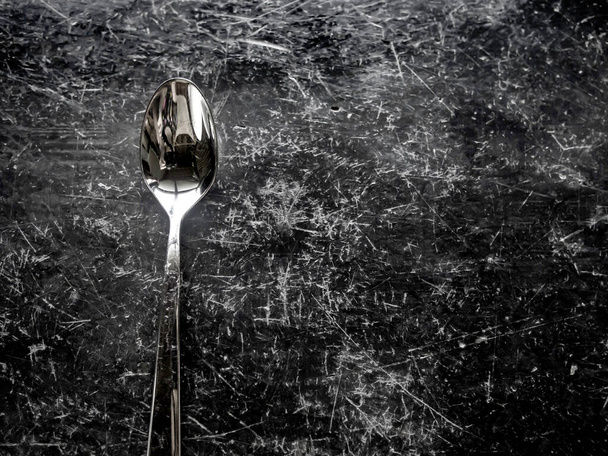 Metal spoon on black polished stone table - Zdjęcie, obraz