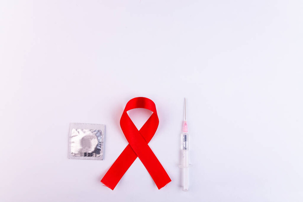 Top view of a red ribbon, condom and syringe on a white background - Foto, Bild