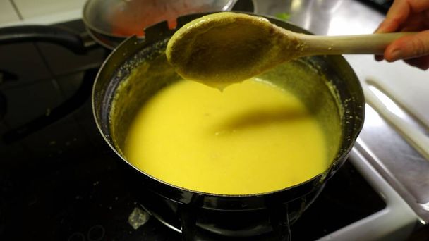 De polenta die in een pan wordt gekookt, moet continu met een houten lepel worden geroerd. - Foto, afbeelding