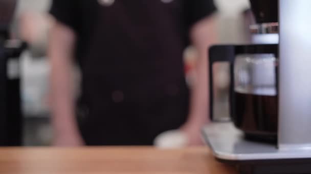 detailní záběr na kávu v plechovce s kávou uvnitř na dřevěném stole v kavárně prostředí kavárny. mužská ruka držící džbánek - Záběry, video