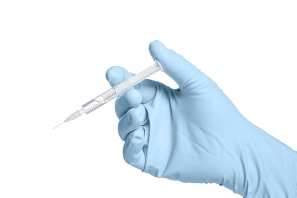 Ένα αρσενικό χέρι σε ένα μπλε γάντι κρατά μια σύριγγα με ένα διαφανές υγρό που απομονώνεται σε λευκό φόντο. - Φωτογραφία, εικόνα