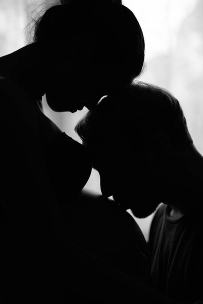 Multi ethnic couple married and in love in silhouette by the window - Fotó, kép