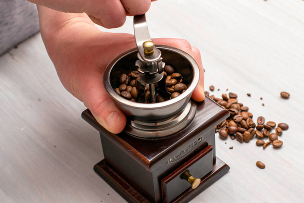 Mann mahlt Kaffeebohnen in einer manuellen Kaffeemühle - Foto, Bild