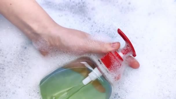 Botellas de detergentes flotan en la espuma. El concepto de los peligros de los productos químicos domésticos. Laureado de sodio, parabenos, sulfatos y otros compuestos químicos en la espuma. Jabón líquido en un frasco amarillo - Imágenes, Vídeo