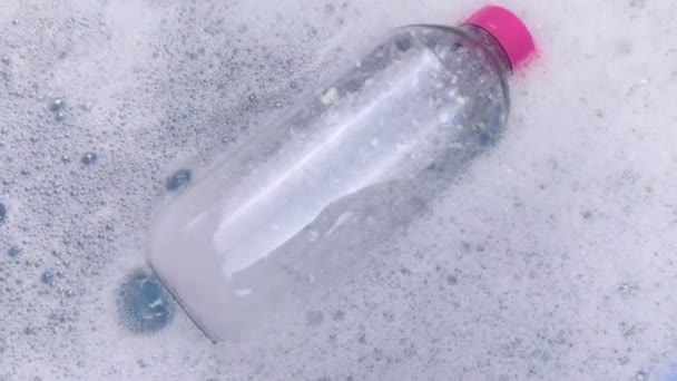 Köpükte bir şişe deterjan yüzüyor. Evdeki kimyasalların tehlikeleri kavramı. Köpükteki sodyum ödüllü maddeler, parabenler, sülfatlar ve diğer tehlikeli kimyasal bileşikler. Micellar suyu - Video, Çekim