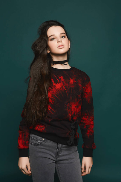 Young brunette teen model girl posing at dark-green background - Valokuva, kuva