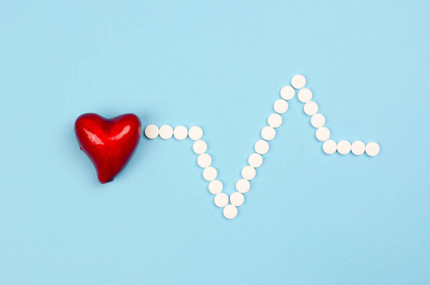 Piros szív és tabletták formájában kardiogram kék alapon - Fotó, kép