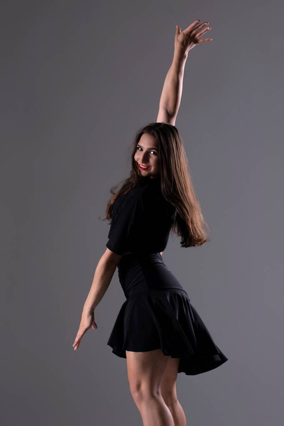 Νεαρή επαγγελματίας χορεύτρια σε στούντιο, Νεαρή γυναίκα με μαύρο φόρεμα που χορεύει, χορεύτρια - Φωτογραφία, εικόνα