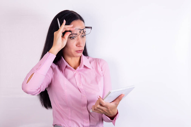 Picture of a surprised business woman with glasses looking in notebook on white background - Photo, image