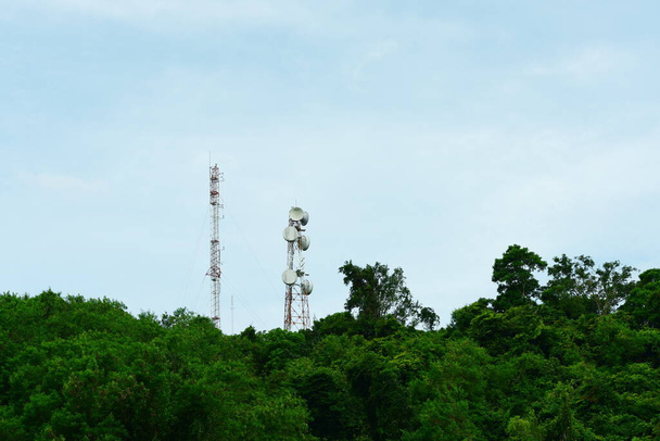 緑の森の中にアンテナのある高電圧タワー - 写真・画像