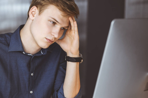 Young blond businessman feeling stress at workplace in office. Startup business means working hard and out of time for success achievement - Photo, image