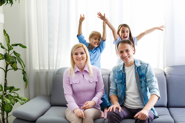 Χαρούμενη οικογένεια με παιδιά να γελάνε καθισμένοι στον καναπέ μαζί, γονείς με παιδιά να διασκεδάζουν στο σπίτι - Φωτογραφία, εικόνα