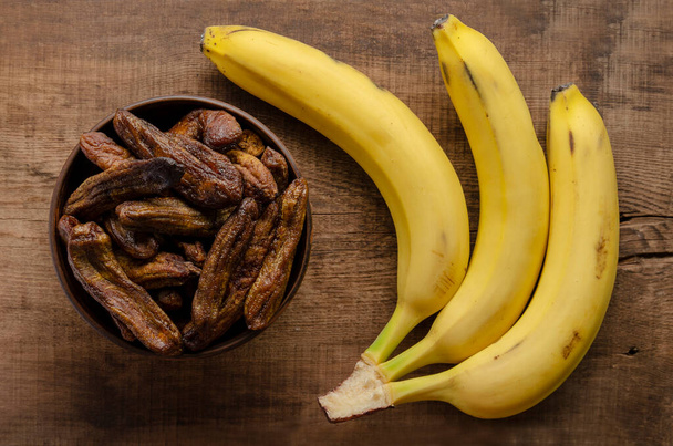 Banane secche nella ciotola con banane fresche su legno - Foto, immagini