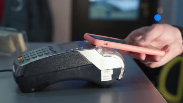 Płatność za pomocą smartfona. Męska ręka płaci za pomocą systemu NFC w telefonie komórkowym. Płatności zbliżeniowe. - Materiał filmowy, wideo