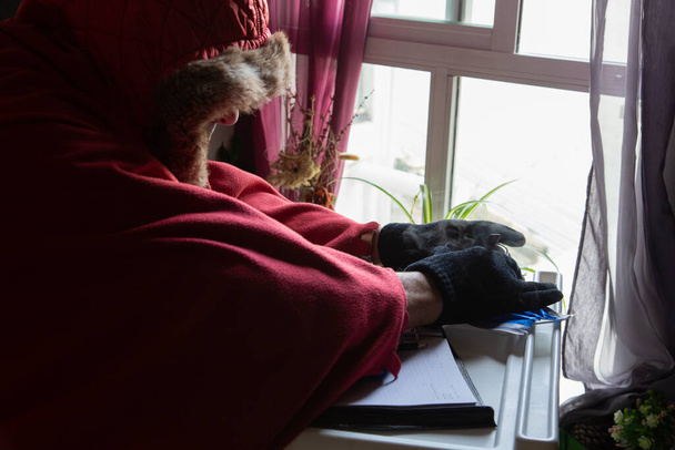 Az öregember nagyon melegen otthon dolgozik a hidegben. - Fotó, kép