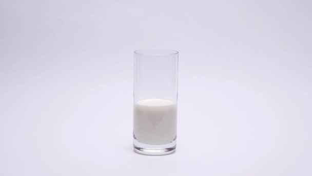 Lasi tuoretta maitoa valkoisella pohjalla. Pysäytä liikeanimaatio  - Materiaali, video