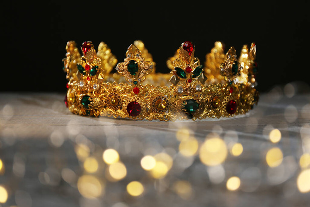 Beautiful golden crown and fairy lights on black background. Fantasy item - Fotoğraf, Görsel