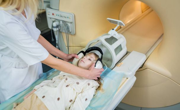 Radiologist prepares the little girl for an MRI brain examination - 写真・画像