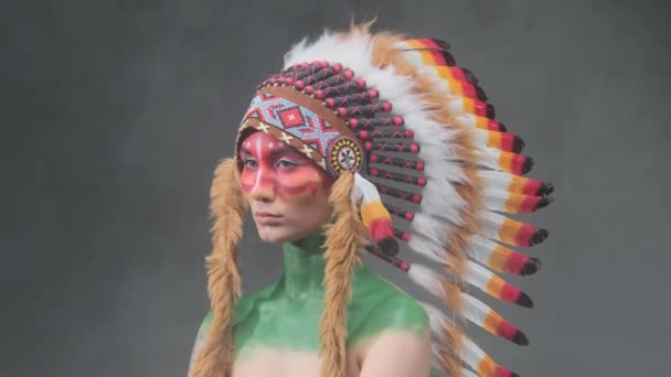Schöne Frau mit indischer Stammeskopfbedeckung posiert vor dunklem Smokey-Hintergrund - Filmmaterial, Video