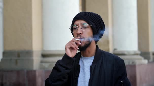 Tyylikäs mietteliäs mies ottaa savukkeen puhalluksen hidastettuna, tupakoi kadulla - Materiaali, video